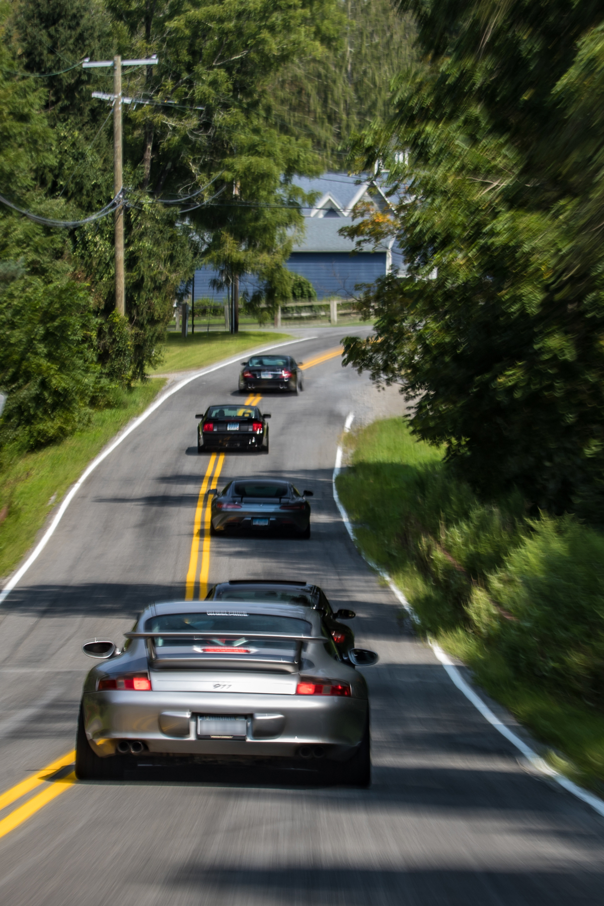 Convoy seen from above, cars strung along a summer road