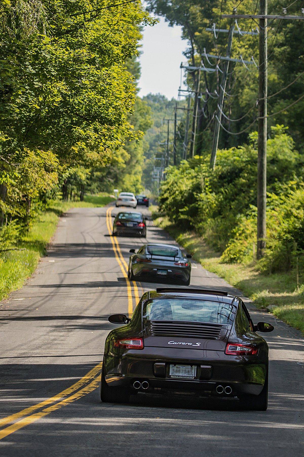 Trailing a brown 911 down a summer road, cars strung out ahead