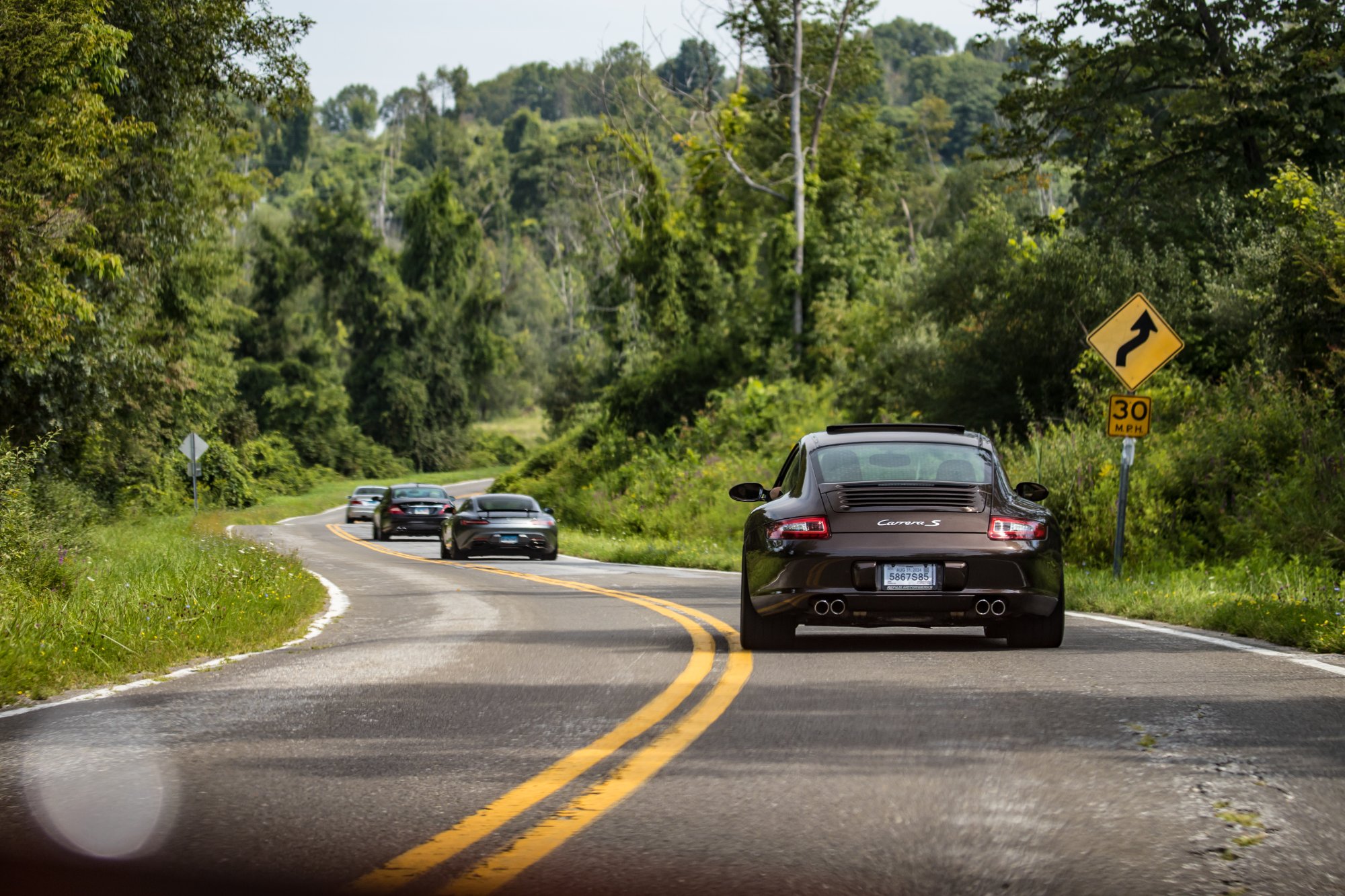 Porsche Carrera S leading group through a winding road