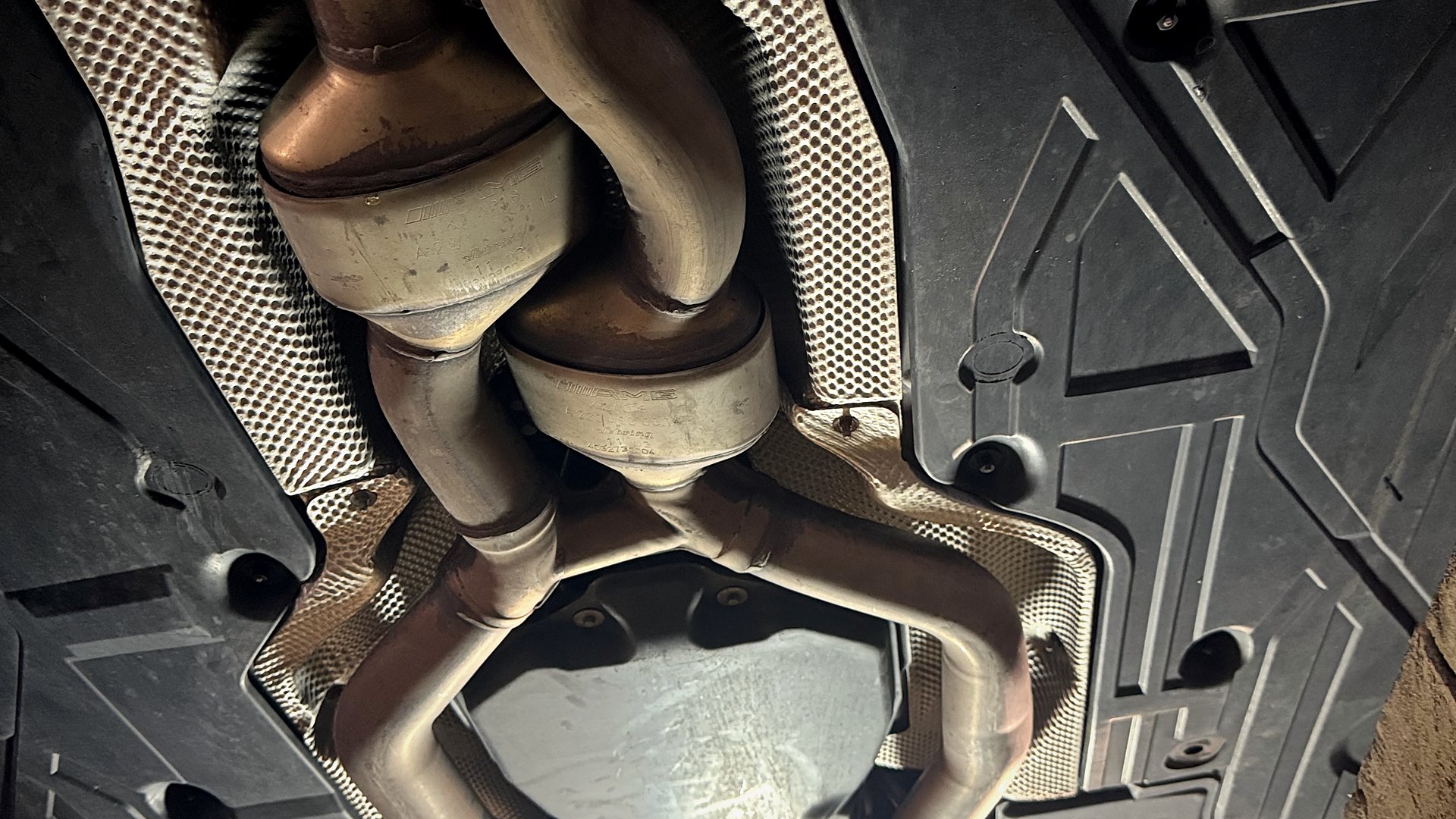 An AMG exhaust system seen from underneath, on a lift.