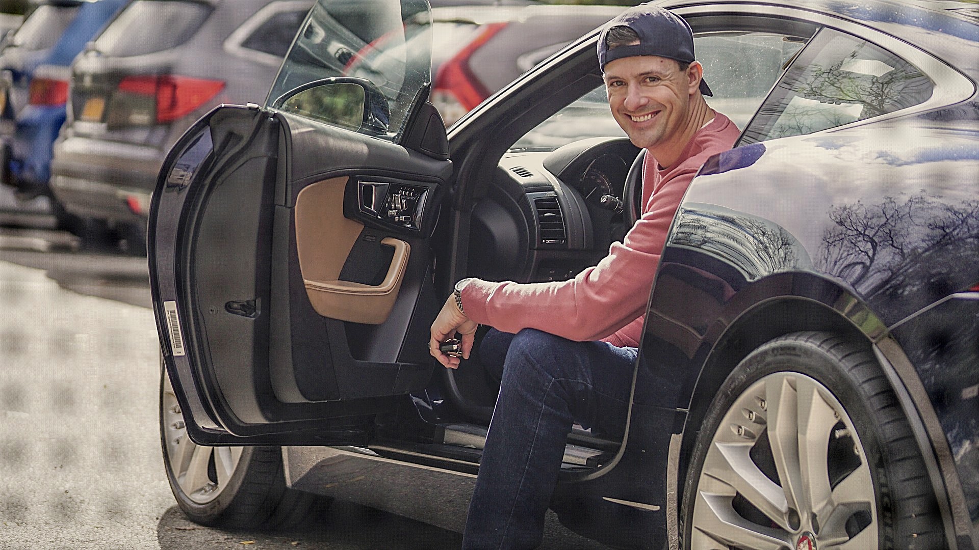 The founder seated in the open door of his Jaguar F-Type at a drive.